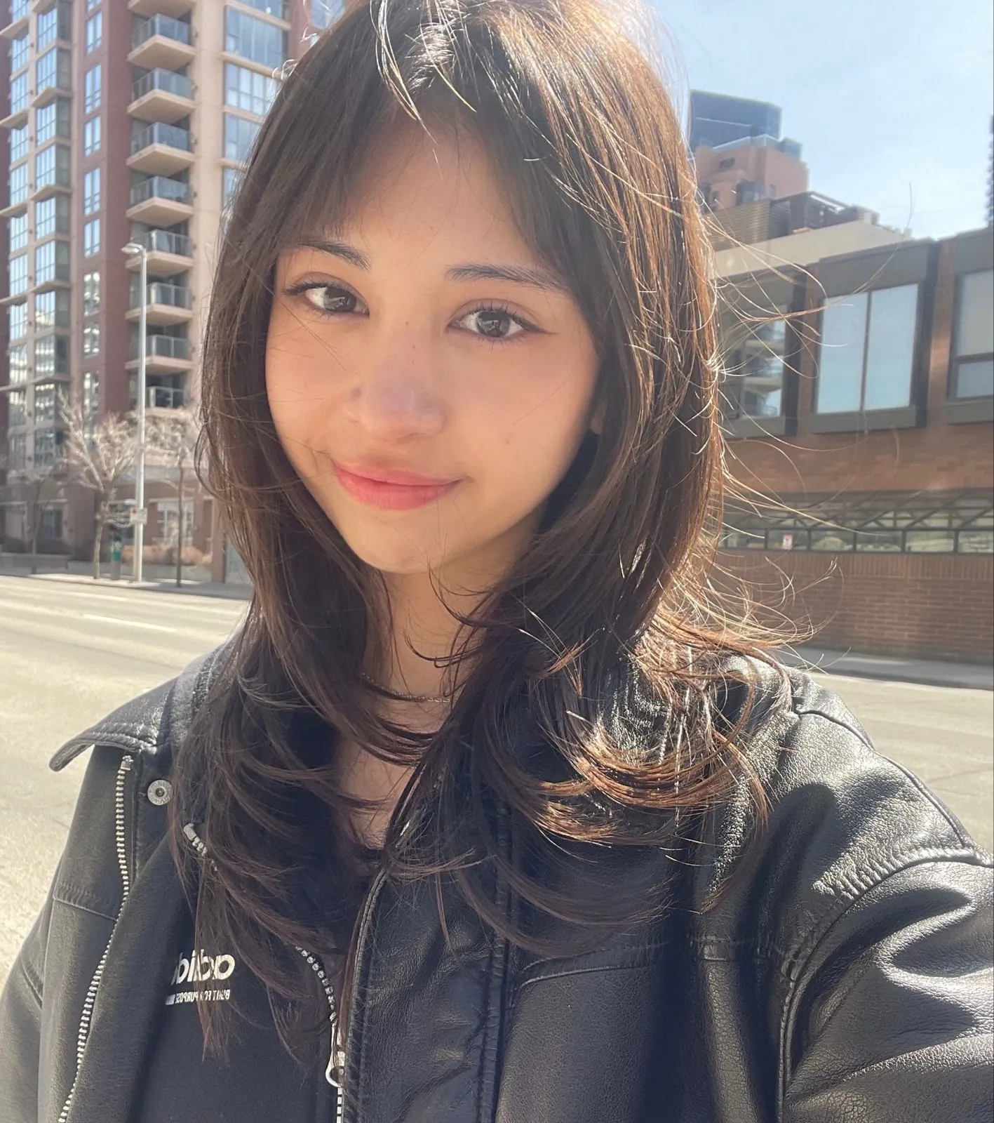 Portrait of Andrea Gutierrez on a sunny Calgary street, wearing a black leather jacket
